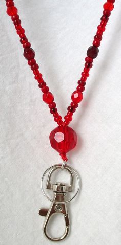 Red Beaded Lanyard This Red Beaded Lanyard can be used as a badge holder, an I.D. holder, keychain necklace, watch holder - it's a multi-use accessory for home or office! 34" in length, long enough to put on or remove overhead. It also has an easy-to-use metal lobster clasp for your convenience. It's made with red glass beads and strung on strong C-Lon beading cord. Snap-on badge holder, clip, and keyring are included to keep your badges or keys ready when you need them. This Red Beaded Lanyard Adjustable Red Lanyard With Key Leash, Red Lanyards With Key Leash, Red Lanyard With Key Leash As Gift, Red Lanyards With Key Leash For Gifts, Adjustable Red Lanyard As Gift, Keychain Necklace, Lanyard Necklace, Beading Cord, Beaded Lanyard