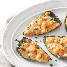 four stuffed peppers on a white plate with green garnish and parmesan cheese