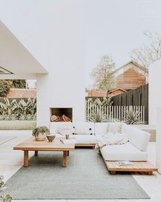 a living room filled with white furniture next to a wooden table and fire place on top of a hard wood floor