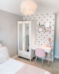 a bedroom with a white desk, pink chair and mirror on the wall next to it