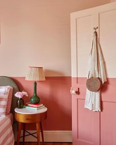 a bedroom with pink walls and a green lamp next to a bed on a wooden floor