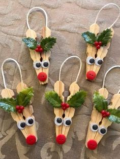 four popsicle reindeers with holly leaves and red noses are hanging on a wall