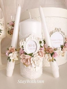 three candles are sitting next to each other with flowers on them and lace around the candle holders