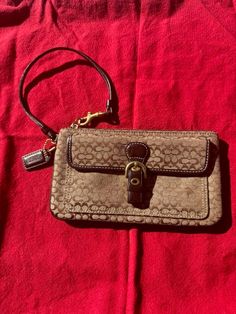 This cute little Coach, wristlet clutch is in like new condition. I did not find any flaws or stains on the inside or out. The center compartment will hold an iPhone.  This purse is 8" wide by 4.75" tall and the bottom measure .5" deep. Formal Clutch Wristlet With Zipper Closure, Brown Clutch Wristlet With Cell Phone Pocket, Wristlet Clutch, Coach Wristlet, Wristlets, Purses And Handbags, Like New, Purse, Purses And Bags