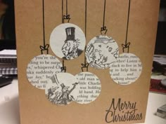 a brown card with three christmas ornaments hanging from it's sides and the words merry christmas written in black ink