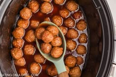 the meatballs are being cooked in the slow cooker with a wooden ladle