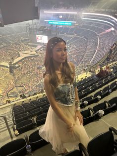 a young woman standing in front of an empty stadium filled with seats and people sitting on the bleachers