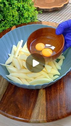 a person in blue gloves is dipping eggs into a bowl