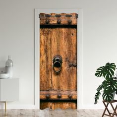 an old wooden door with a round knob on the front and side, in a white room