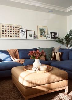 a living room with blue couches and pictures on the wall above it's coffee table