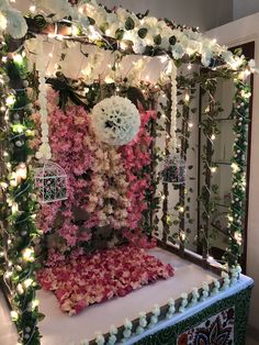 a decorated stage with pink and white flowers on the top, surrounded by greenery