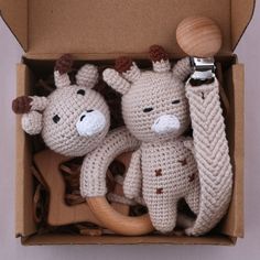 two crocheted giraffes in a cardboard box with a wooden handle