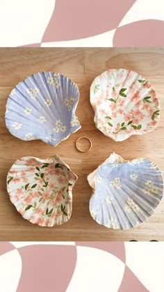 four seashells are sitting on a wooden table