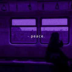 a person sitting on a bench in front of a window with the words peace written across it