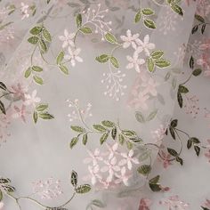 the fabric has flowers on it and is white with green leaves in pastel colors