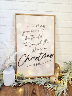 a christmas sign on top of a wooden table next to a white and gold decoration