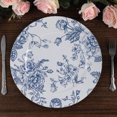 a blue and white plate sitting on top of a wooden table next to pink roses