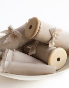 rolled up napkins are sitting on a white plate with wooden buttons and ribbons tied around them