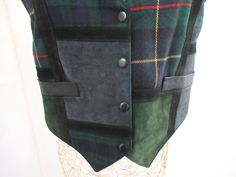 Vintage womans leather suede and plaid wool vest, This vest is in great condition. Brandon Thomas Black leather, black, gray, green suede and green plaid. Navy blue back with elastic. Size M. Chest 38 inches. Front 4 snaps closure. good size front pockets. dry clean. I am happy to answer questions and combine shipping. All items are from a smoke free pet free home. Vintage Winter Vest With Button Closure, Fitted Sleeveless Plaid Vest, Green Sleeveless Patchwork Vest, Blue Patchwork Sleeveless Vest, Blue Sleeveless Patchwork Vest, Holiday Vest, Gray Leather Shoes, Paisley Pillows, Plaid And Leather