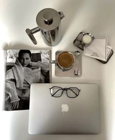 an open laptop computer sitting on top of a white desk next to a cup of coffee