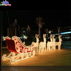 a lighted sleigh with reindeers and trees in the background