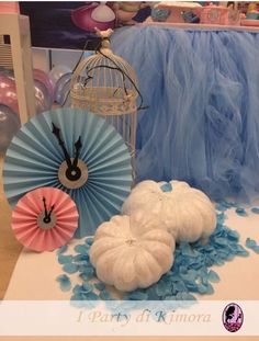 decorative items displayed on table with blue and pink decorations in the background, including paper fans