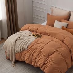 a bed with an orange comforter and pillows