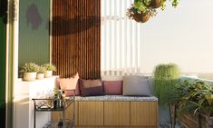 a balcony with potted plants and wooden slats on the wall, next to a bench