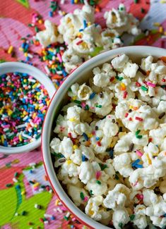 a bowl filled with sprinkles and popcorn on top of a wooden table