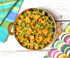 a bowl filled with green beans and carrots on top of a colorful table cloth