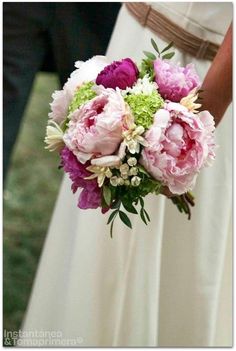 a bride holding a bouquet of pink and green flowers