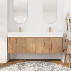 a white bathroom with two mirrors above the sink and a rug on the floor next to it