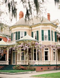 an old victorian house with flowering trees in front