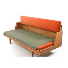 an orange and green couch sitting on top of a wooden frame