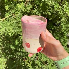 a hand holding up a pink and white cup