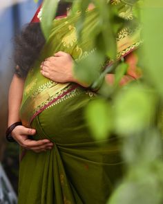 a woman in a green sari hugging another woman