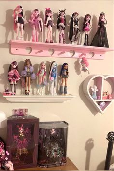 there are many barbie dolls on the shelf above the shelves in this room, all pink and white