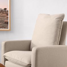 a living room with a chair, table and pictures hanging on the wall above it