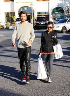 a man and woman walking down the street with shopping bags