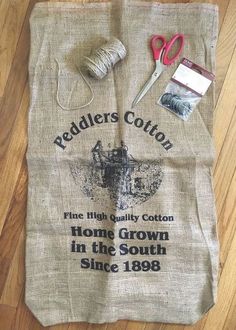 a pair of scissors and some yarn on a wooden floor next to a bag that says redders cotton