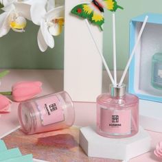 a pink perfume bottle sitting on top of a table next to a box and flowers