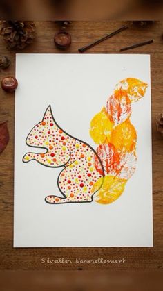 a drawing of a squirrel with autumn leaves and acorns on the table next to it