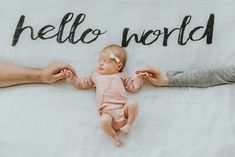 a baby laying on top of a blanket with the words hello world written on it