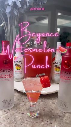 a pink drink sitting on top of a counter next to bottles of watermelon punch