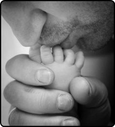 a black and white photo of a man holding a baby's hand