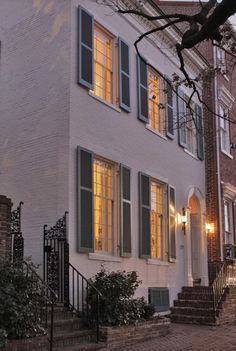 an apartment building with stairs leading up to the front door and windows lit up at night