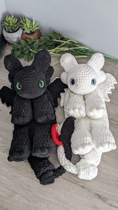 two crocheted stuffed animals sitting next to each other on a wooden floor with succulents in the background