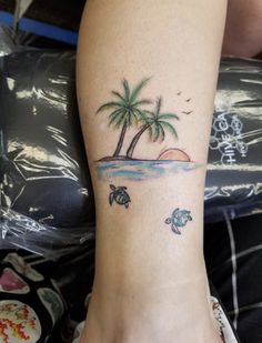 a woman's foot with a palm tree and turtle tattoos on it