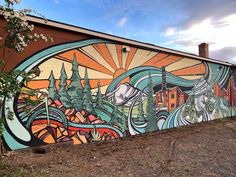 a large mural on the side of a building with trees and buildings in the background