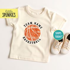 Retro Custom Basketball Tee, Distressed Team Name with Basketball Natural Shirt, Kids Basketball Outfit (DISTRESSED BASKETBALL NAME) PRODUCTION TIME Little Spunkies from the designer/owner of Spunky Pineapple Co https://www.etsy.com/shop/SpunkyPineappleCo   All baby and toddler clothes are 100% designed and printed with water based ink. All orders placed before 12:00 pm EST are shipped out same day (Monday - Friday). Orders received after noon are shipped out the next business day. ONESIES® BRAND Made from 100% Cotton. We print on Onesies® Brand. T-SHIRT Made from 100% Cotton. These run true to size. If you are in between sizes we suggest sizing up. CARE Machine wash in cold water, inside out, and tumble dry.   SHIPPING All orders are shipped out via USPS First Class Mail (3-4 days).   Shi Basketball Outfit, Basketball Tees, Basketball Clothes, Kids Basketball, Custom Basketball, Basketball Shirts, Kids Graphic Tees, Baby And Toddler, Team Name